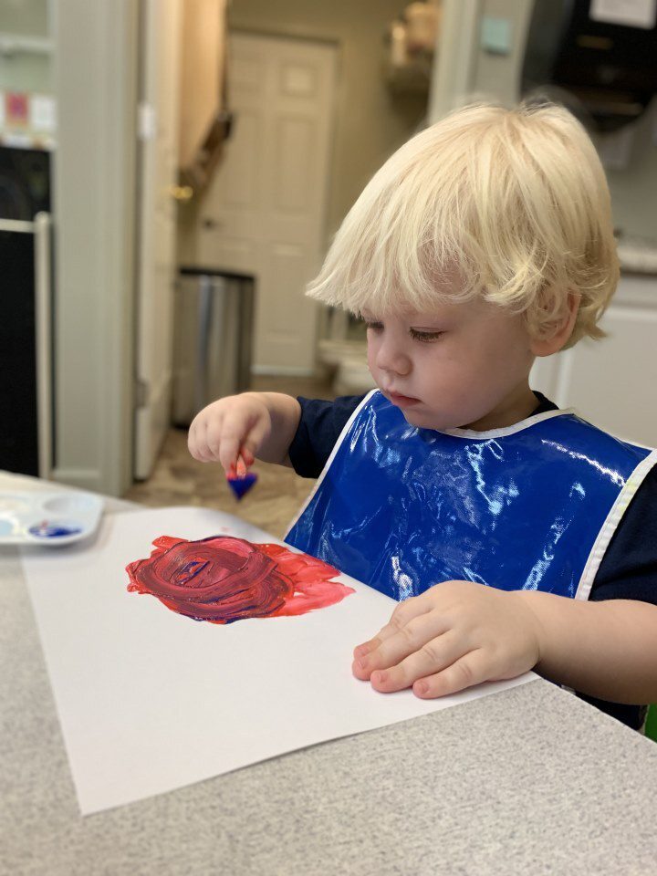 Little boy making art in an infant and toddler program in Hampden